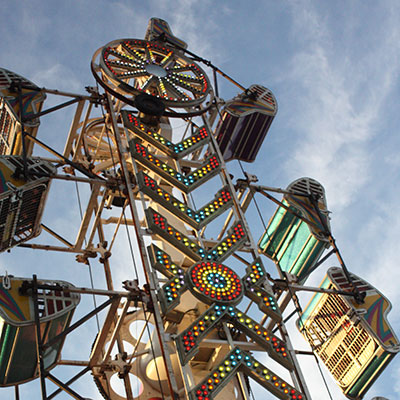 A tall oblong carnival ride with colorful lights and tipsy caged in seats that go around the perimeter